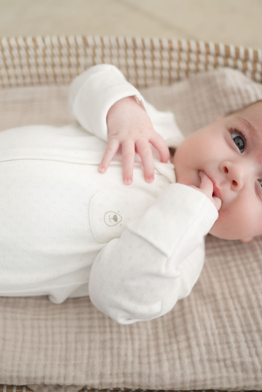 Baby lying on a checkered blanket with a white plush toy