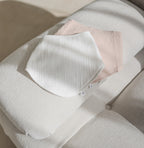 White and pink baby bibs on a light beige surface