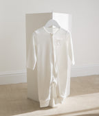 White baby onesie on a hanger against a white wall