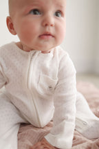 Baby wearing a white outfit with a blurred background