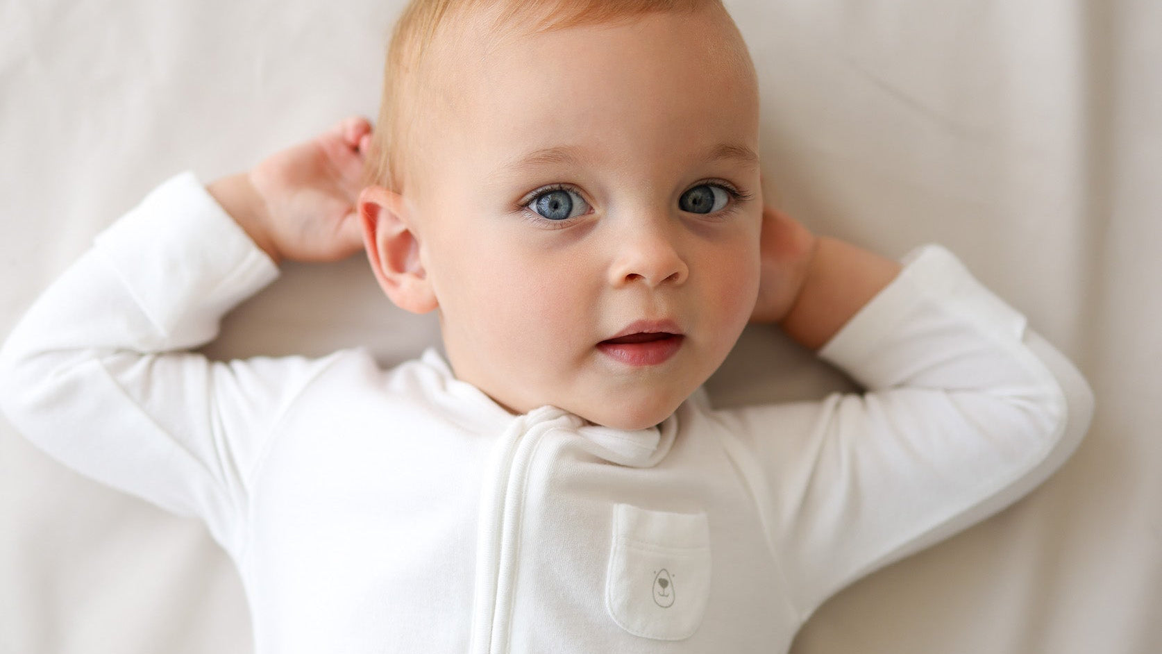 Baby wearing a white onesie with buttons on a light background