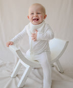 Baby on rocking horse in full white
